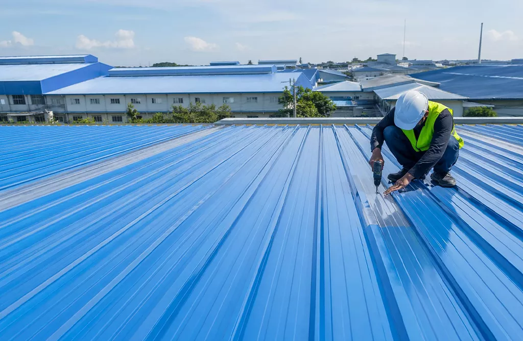 Worker installing FRP roofing sheet on industrial factory building